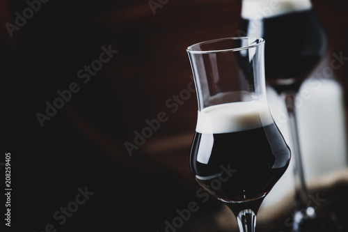 Two-layer cocktail with coffee liqueur, vintage wood background, selective focus photo