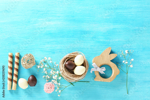 Beautiful composition with chocolate Easter eggs and decorative bunny on color wooden background