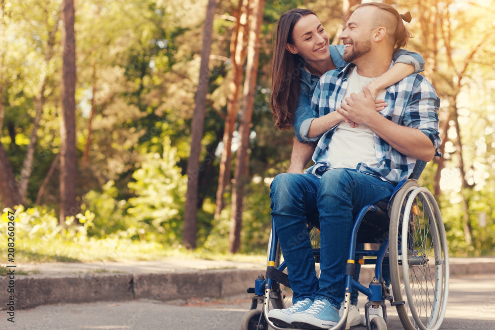 Romantic date. Joyful attractive good looking woman hugging her boyfriend and smiling while being in the park with him Romantic date. Joyful attractive good looking woman hugging her boyfriend and smiling while being in the park with him