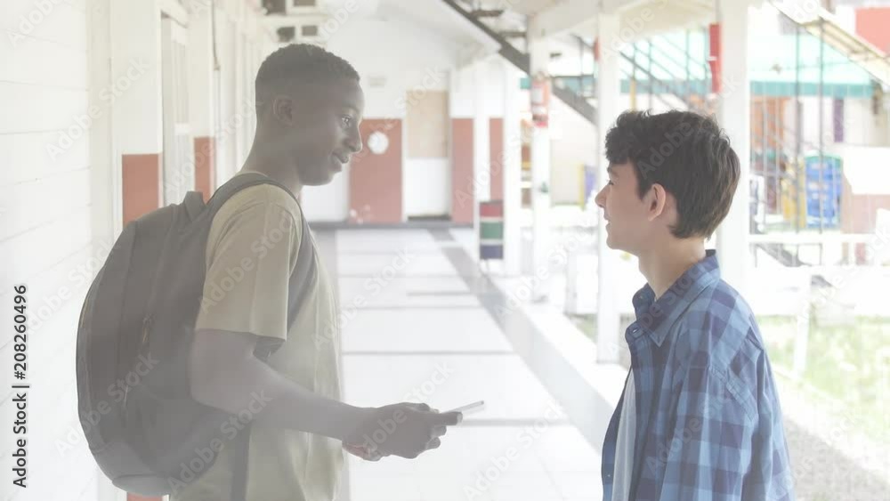 Caucasian and african schoolmates meeting in school hallway with light rays coming from outside Caucasian and african schoolmates meeting in school hallway with light rays coming from outside