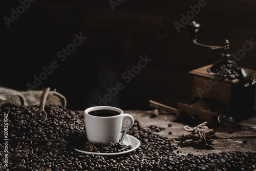 Cup of coffee with coffee beans and grinder on wooden table