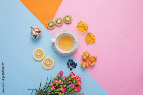 A glass of hot tea with dried fruits and glasses, flower decorated on mix color crop background.