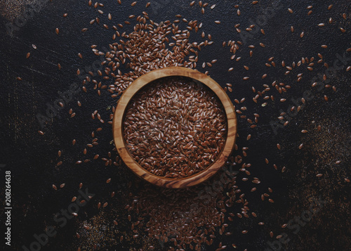 Raw flax seeds in bowl, stone background, top view