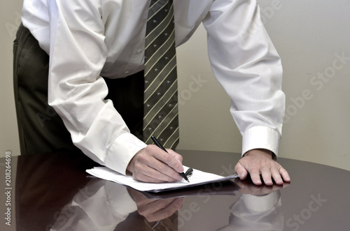 Man Standing at Desk with Contract Papers Signing Documents