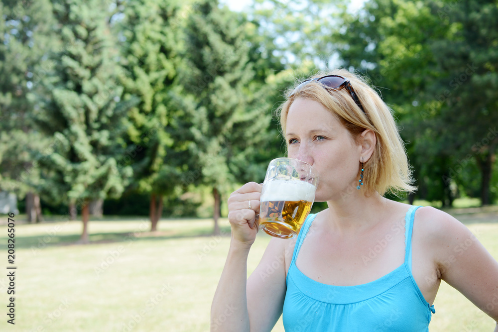 Portrait of happy woman holding glass of beer outside on sunny day. Portrait of happy woman holding glass of beer outside on sunny day.