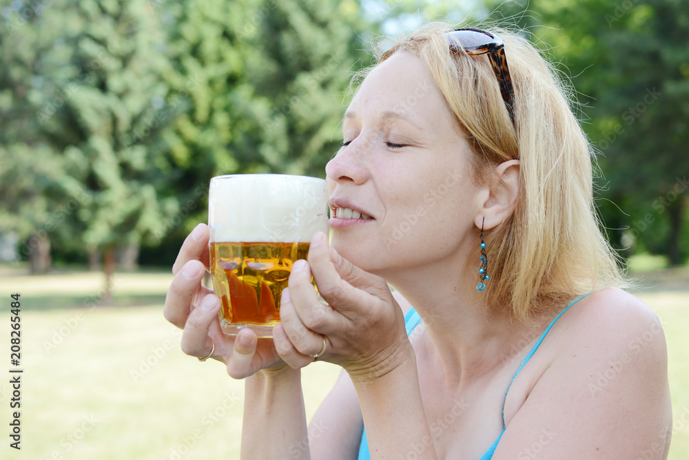Portrait of happy woman holding glass of beer outside on sunny day. Portrait of happy woman holding glass of beer outside on sunny day.