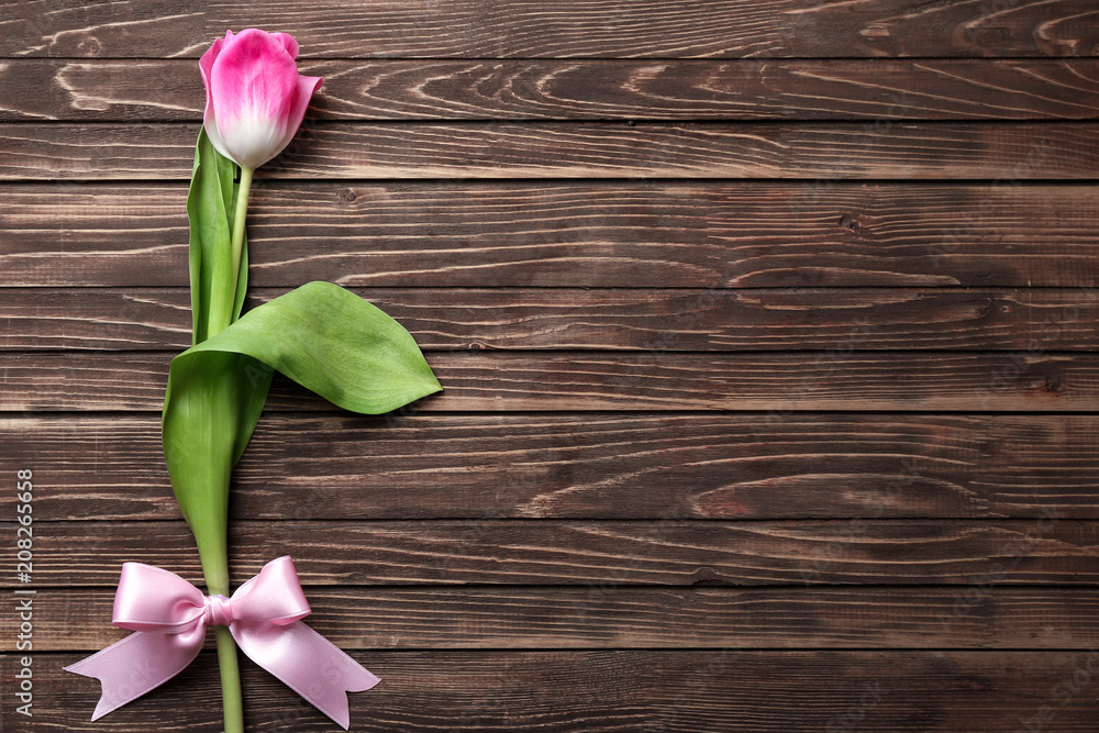 Beautiful tulip with ribbon bow on wooden background