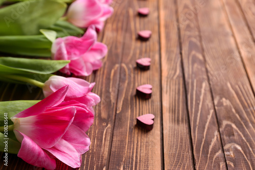 Beautiful tulips and small decorative hearts on wooden background  closeup