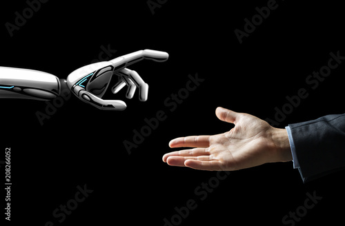 artificial intelligence, future technology and communication concept - robot and human hand over black background