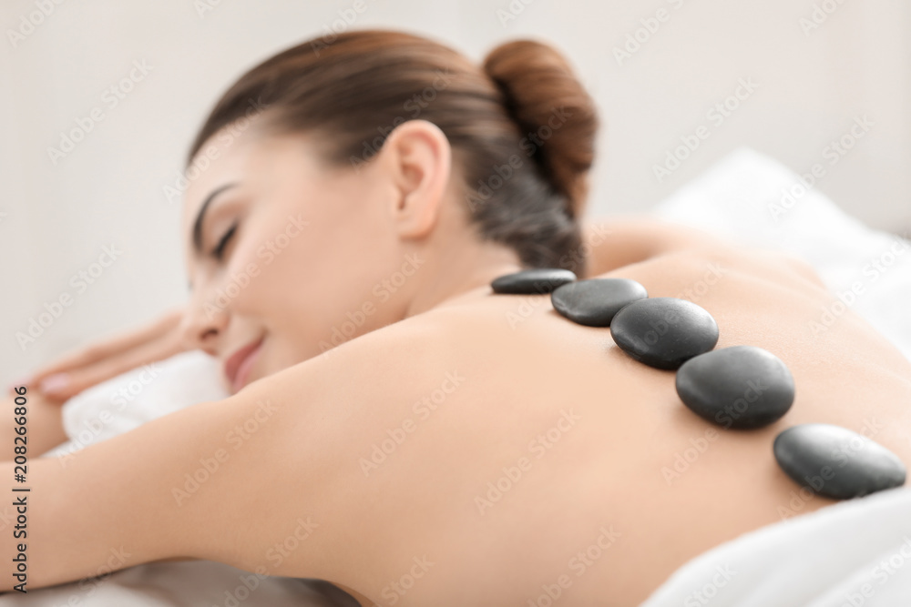 Young woman enjoying stone massage in spa salon