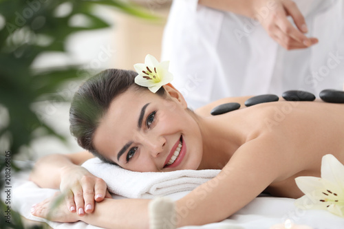 Young woman enjoying stone massage in spa salon