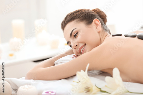 Young woman enjoying stone massage in spa salon