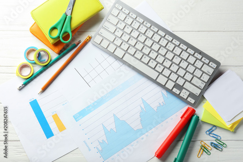 Computer keyboard, documents and stationery on wooden background, flat lay. Workplace table composition