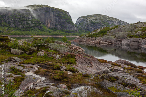 Meditative view of the calm mountain lake with moraine boulders on the shores, Rogaland, Norway