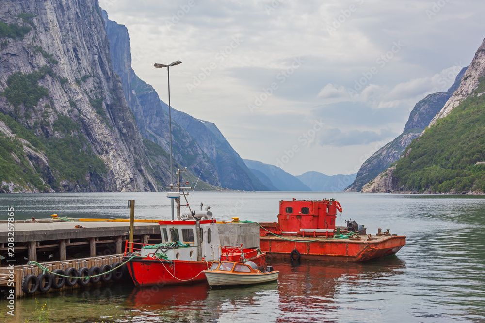 Bright fishing boats and old ferry anchored to the mooring on the norwegian fjord, Norway