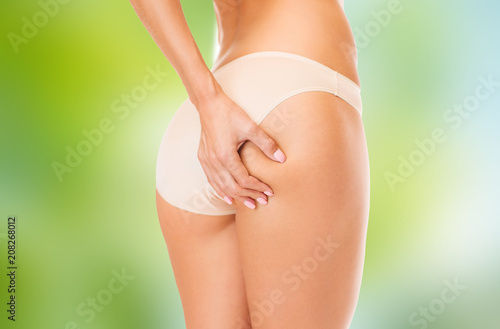 beauty and slimming concept - close up of woman body in cotton underwear over green natural background