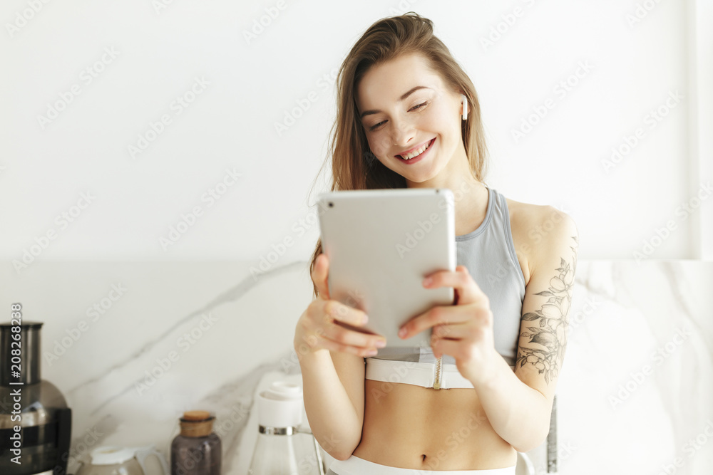 Portrait of beautiful smiling lady in sporty top standing with laptop in hand and earphones isolated Portrait of beautiful smiling lady in sporty top standing with laptop in hand and earphones isolated
