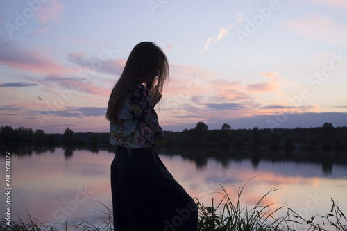 A girl enjoying summer sunset near lake. 