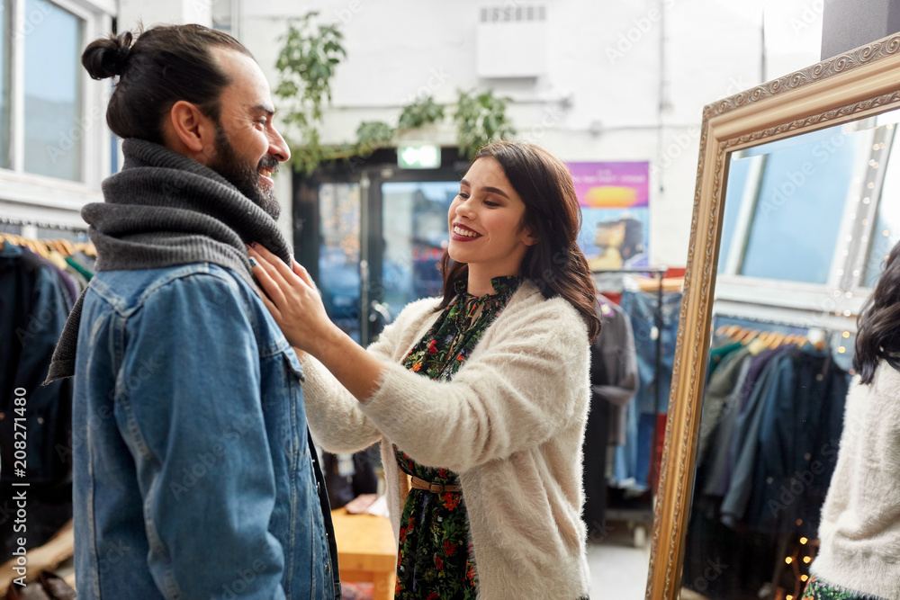 Fototapeta premium sale, shopping, fashion and people concept - couple choosing clothes at vintage clothing store