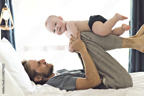 Father playing with adorable baby girl in bedroom