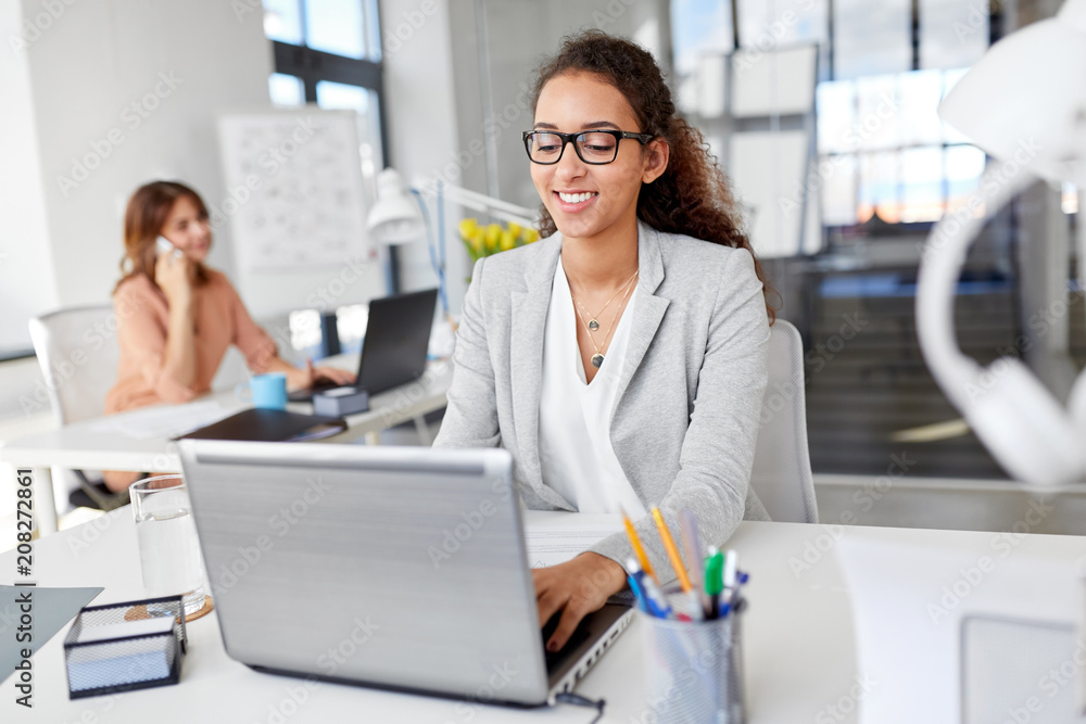 business, technology and people concept - smiling businesswoman in glasses with laptop computer working at office business, technology and people concept - smiling businesswoman in glasses with laptop computer working at office