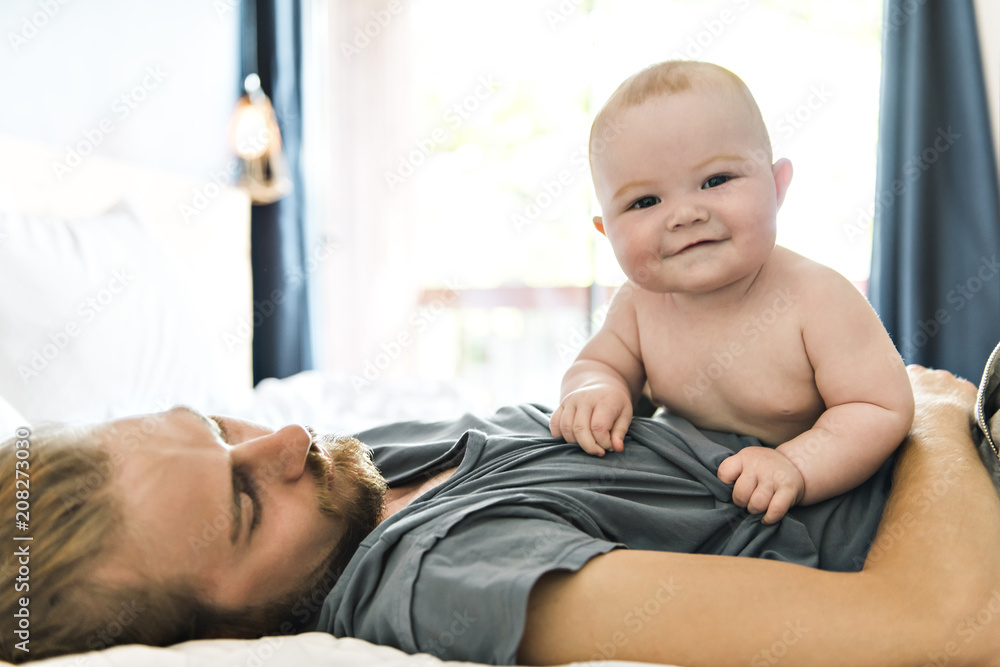 Fototapeta premium Father playing with adorable baby girl in bedroom