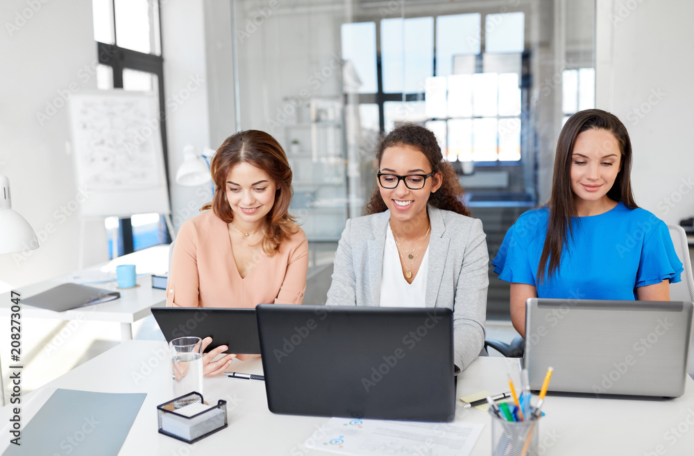 business, teamwork and people concept - female team or businesswomen with tablet pc and laptop computers working at office business, teamwork and people concept - female team or businesswomen with tablet pc and laptop computers working at office