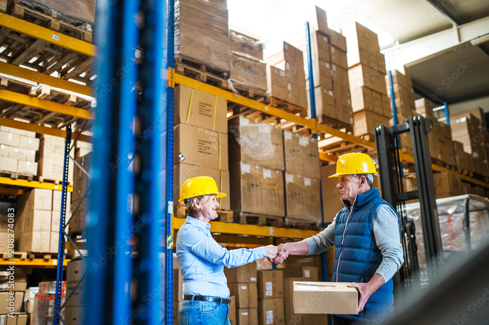 Senior woman managers or workers working in a warehouse, shaking hands. Senior woman managers or workers working in a warehouse, shaking hands.