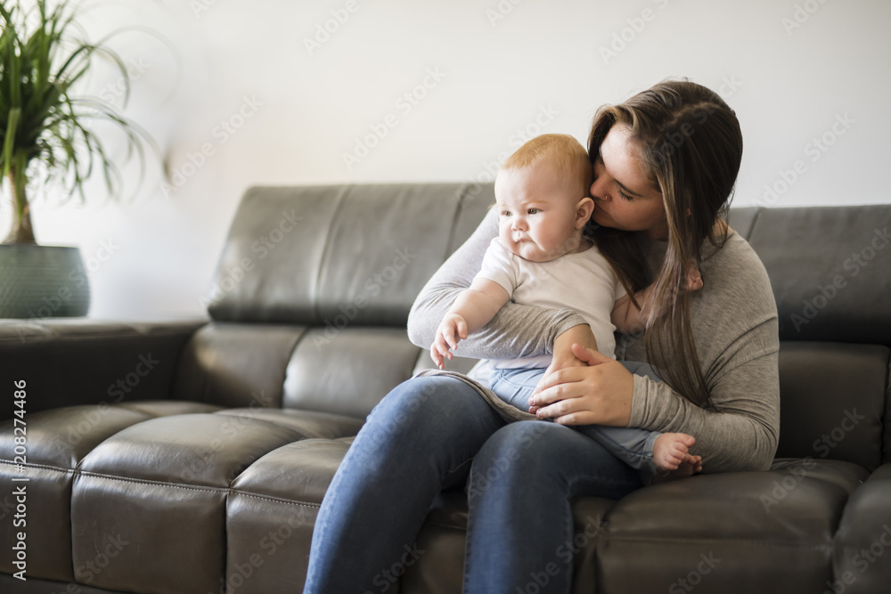 mother with baby daughter on sofa at home