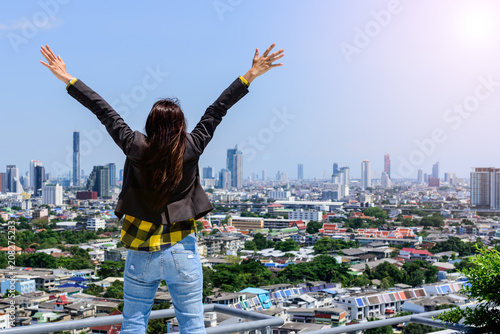 Business woman standing On the rooftop and raising arms when she made the assignment to success. According to the target. or celebrating her freedom