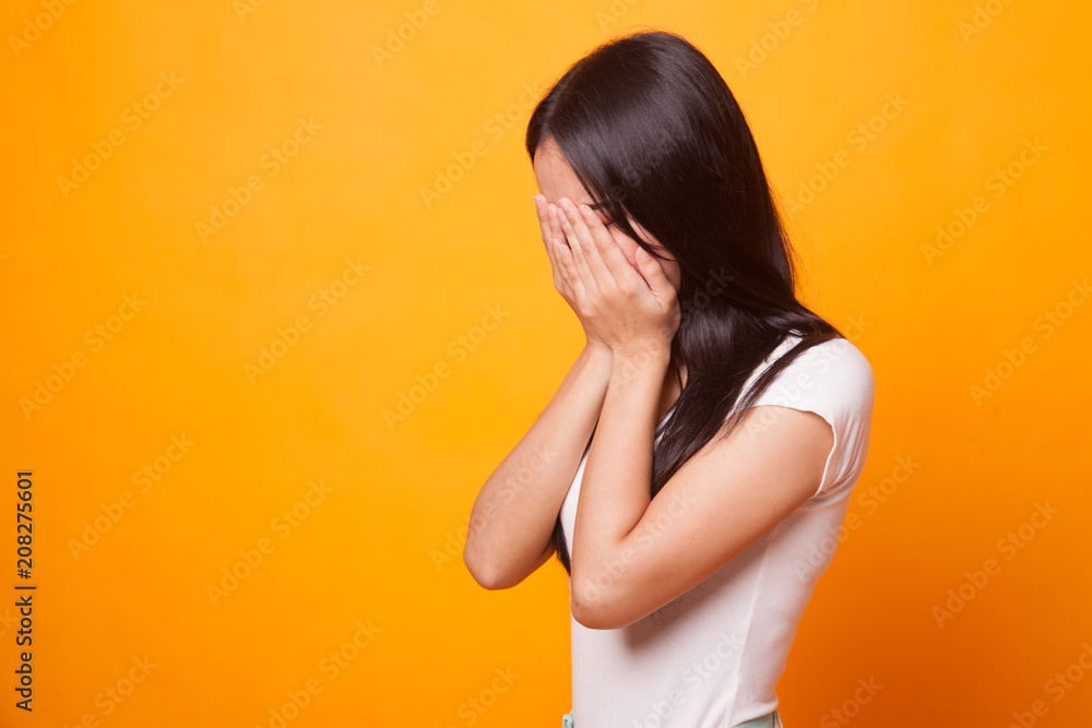 Sad young Asian woman cry with palm to face.