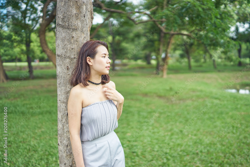 Beautiful asian girl standing alone Lean back tree in park Beautiful asian girl standing alone Lean back tree in park