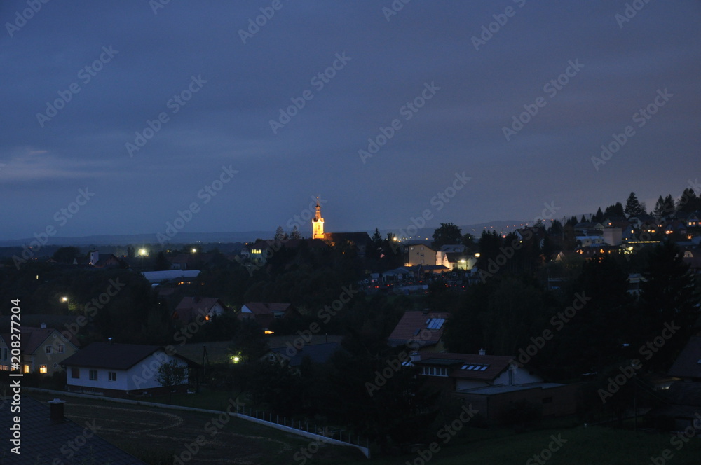 Abendliche Ortschaft mit beleuchtetem Kirchturm