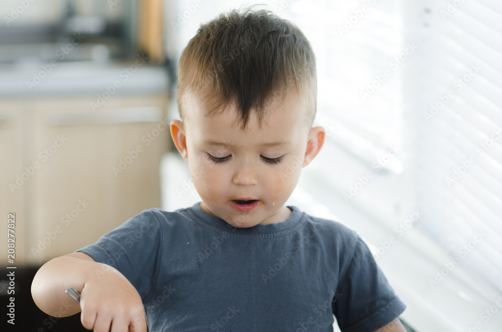 a child in a t-shirt in the kitchen eating an omelet, a fork a child in a t-shirt in the kitchen eating an omelet, a fork