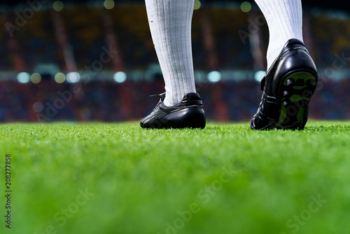 Foot of soccer player or football player walk on green grass ready to play match for the winner with stadium backgrounds.