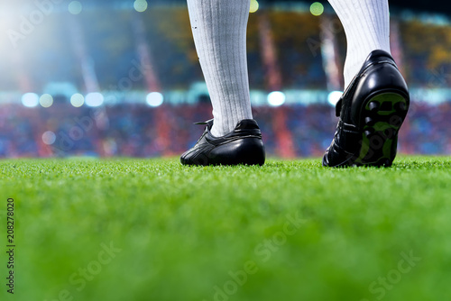 Foot of soccer player or football player walk on green grass ready to play match for the winner with stadium backgrounds.