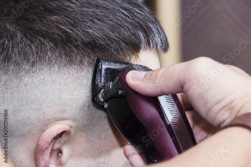 men's hair Styling and grooming with the help of scissors machine and hair clippers in the hair salon.