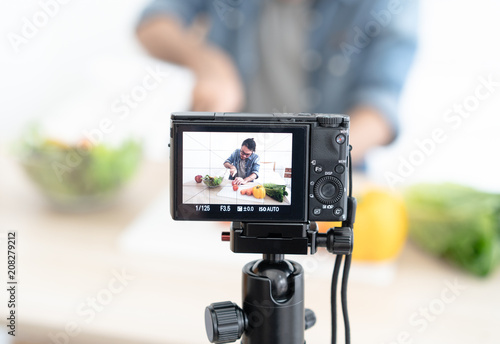 Close up of young Asian smiling blogger with recording video camera filming at home, review healthy man. photo