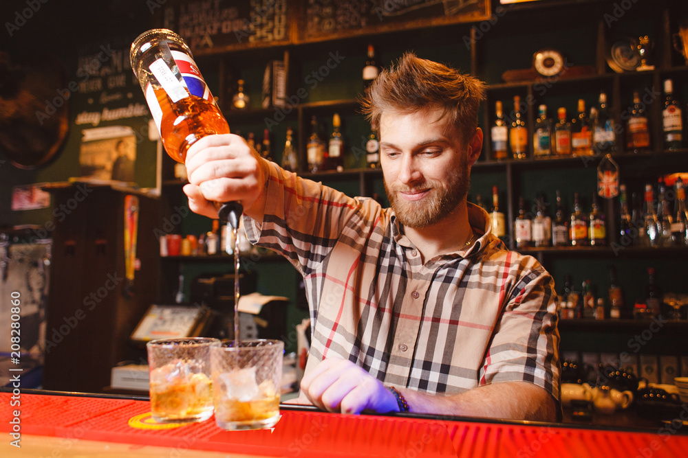 Fotografie A stylish bartender pours whiskey from a bottle
