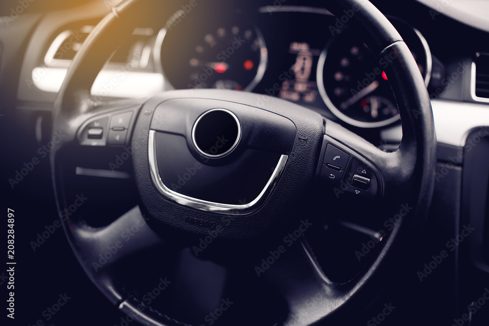 Modern Car Steering Wheel Covered By Leather and Multimedia Dashboard in the Background.