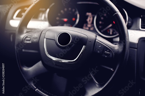 Modern Car Steering Wheel Covered By Leather and Multimedia Dashboard in the Background. © kucheruk