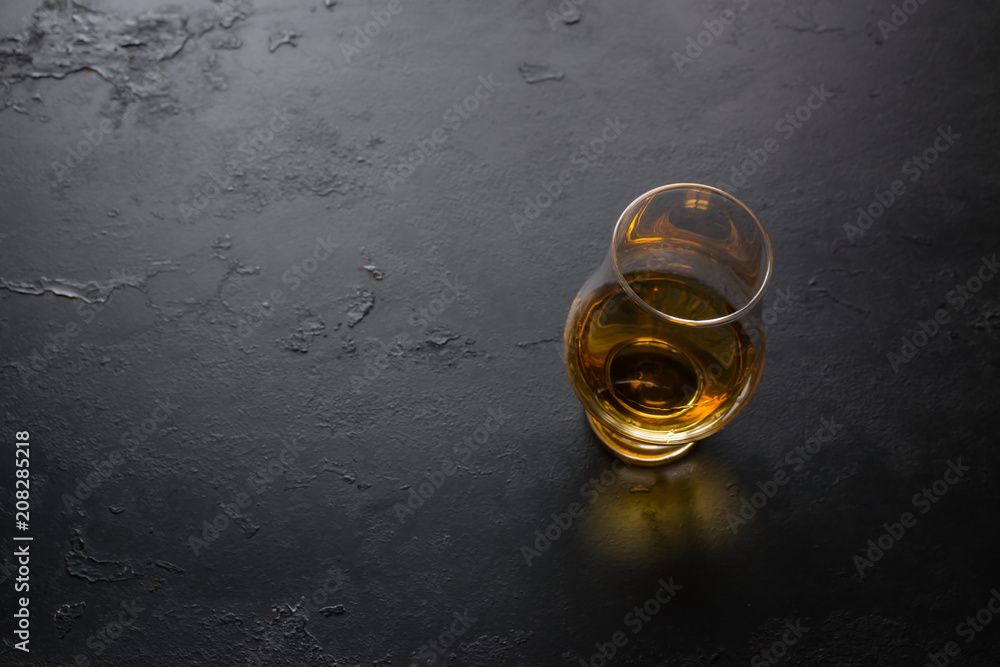 a glass of whiskey on a black background with space for text