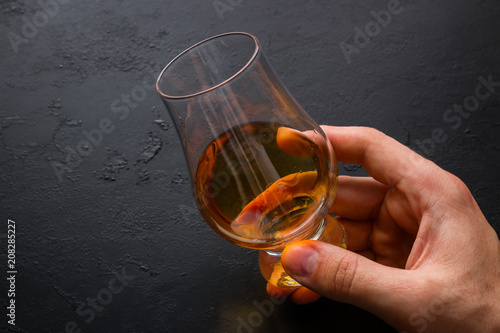 man holding a glass of whiskey on a black background