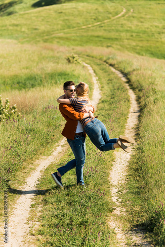 high angle view of young man spinning around girlfriend in rural field