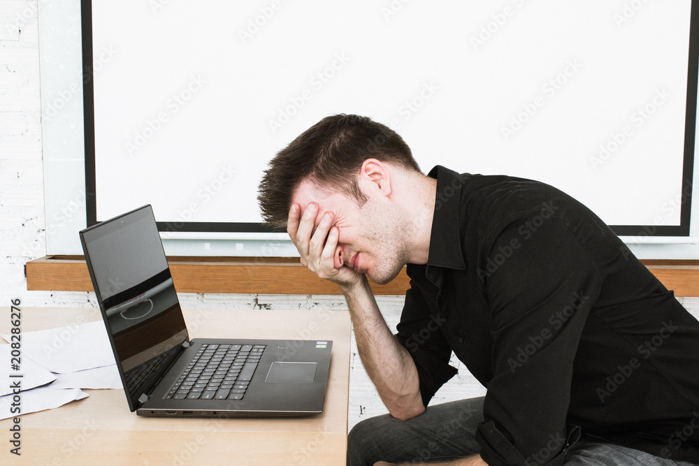Man with headache in office on laptop. Closed eyes and deep in thought. Man with headache in office on laptop. Closed eyes and deep in thought.