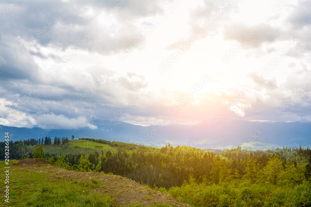 A beautiful mountain landscape - mountains, clouds, clouds, trees, and rays of the sun.