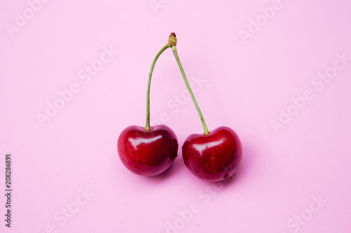 closeup of two cherries on pink background