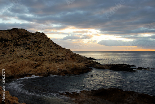 dramatic rocky shoreline with horizon and dark clouded sky beyond