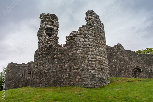 Torlundy, Scotland - June 11, 2012: Ruins of Natural Stone ramparts With Comyn Tower of Inverlochy Castle near Fort William. Outside view with green grass and light gray sky. photo