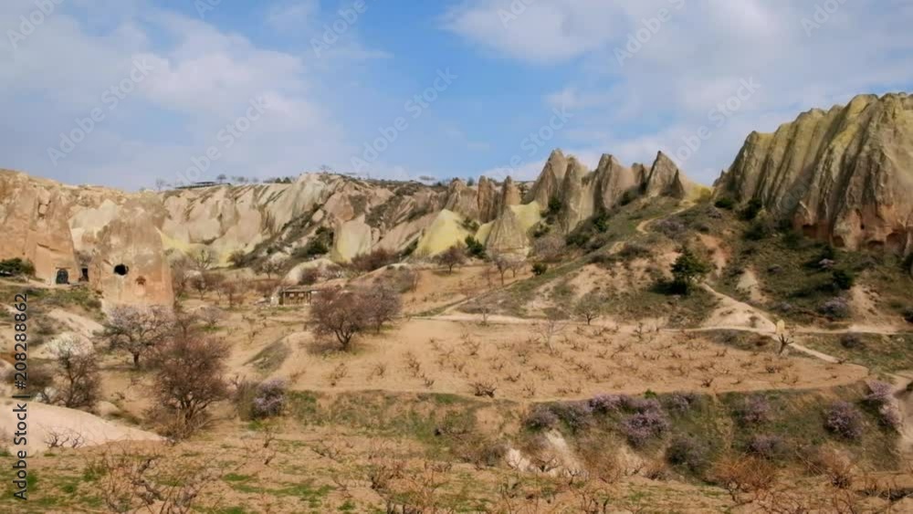 Colorful valley with cave houses and fairy chimneys rock formation with cloudy sky in rural Cappadocia landscape near Goreme village, Turkey Colorful valley with cave houses and fairy chimneys rock formation with cloudy sky in rural Cappadocia landscape near Goreme village, Turkey